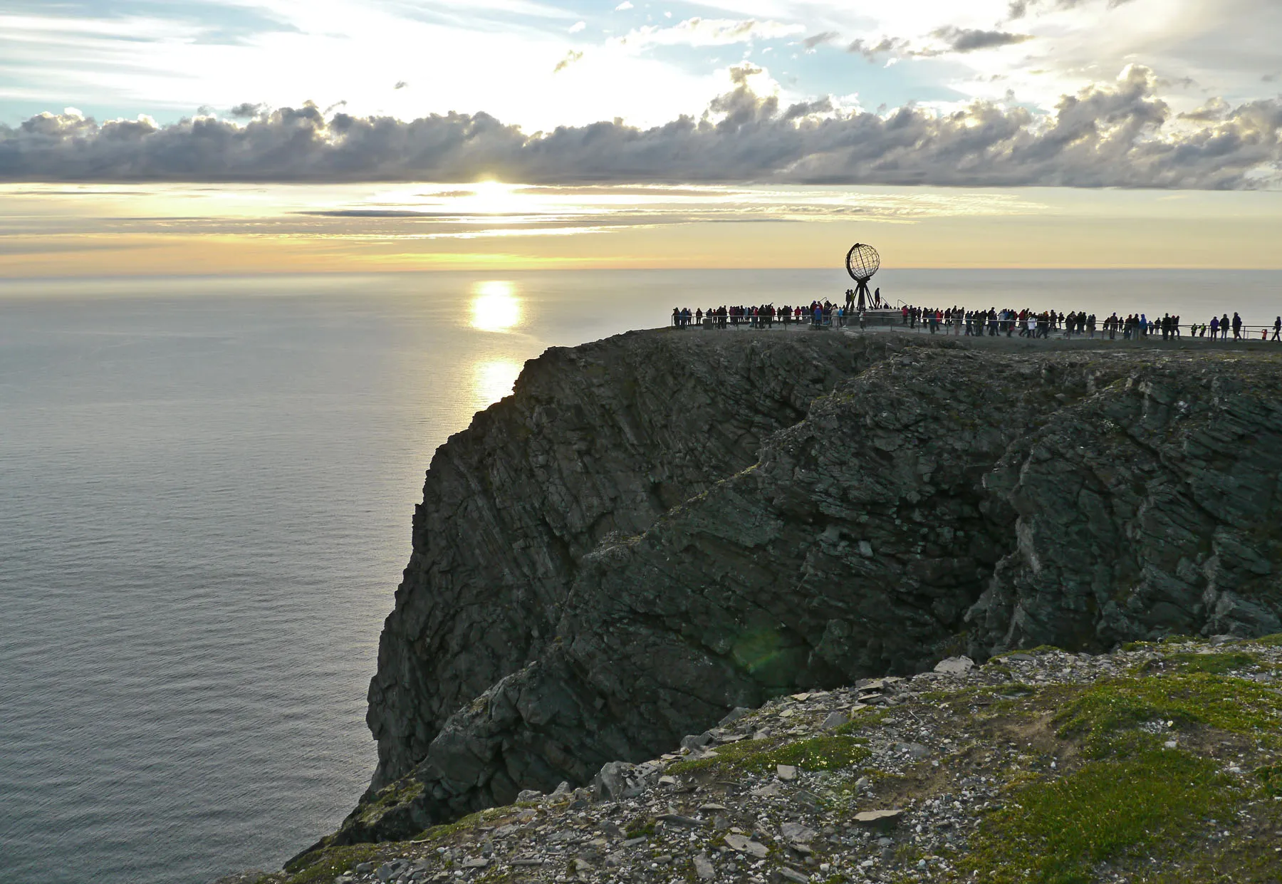 Besucher am Globus auf dem Nordkap-Plateau bei Mitternachtssonne